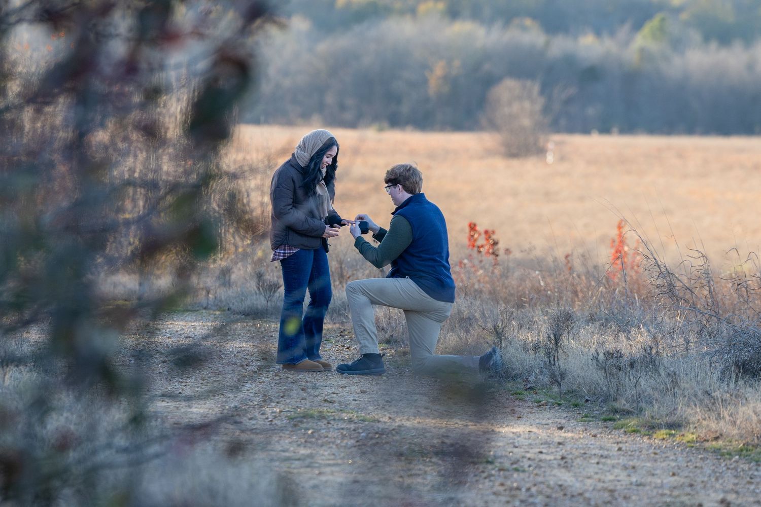 Surprise proposal photographed from afar in a scenic autumn field.
