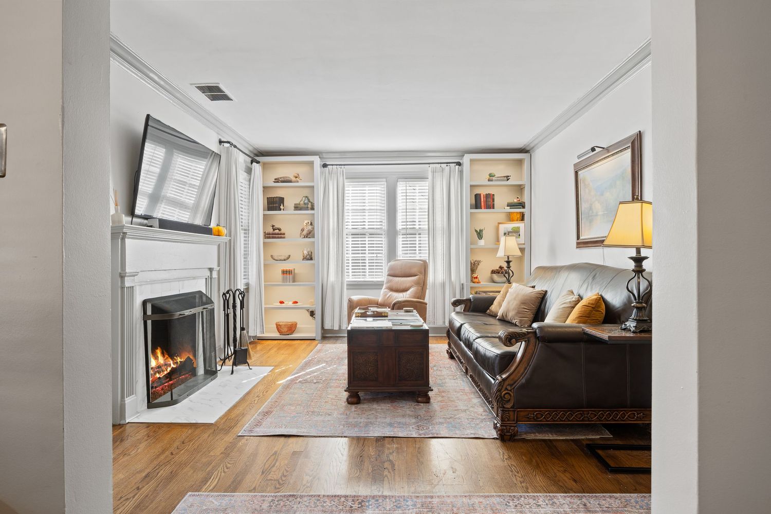 Modern apartment interior with white walls, hardwood floors and natural light streaming through large windows.
