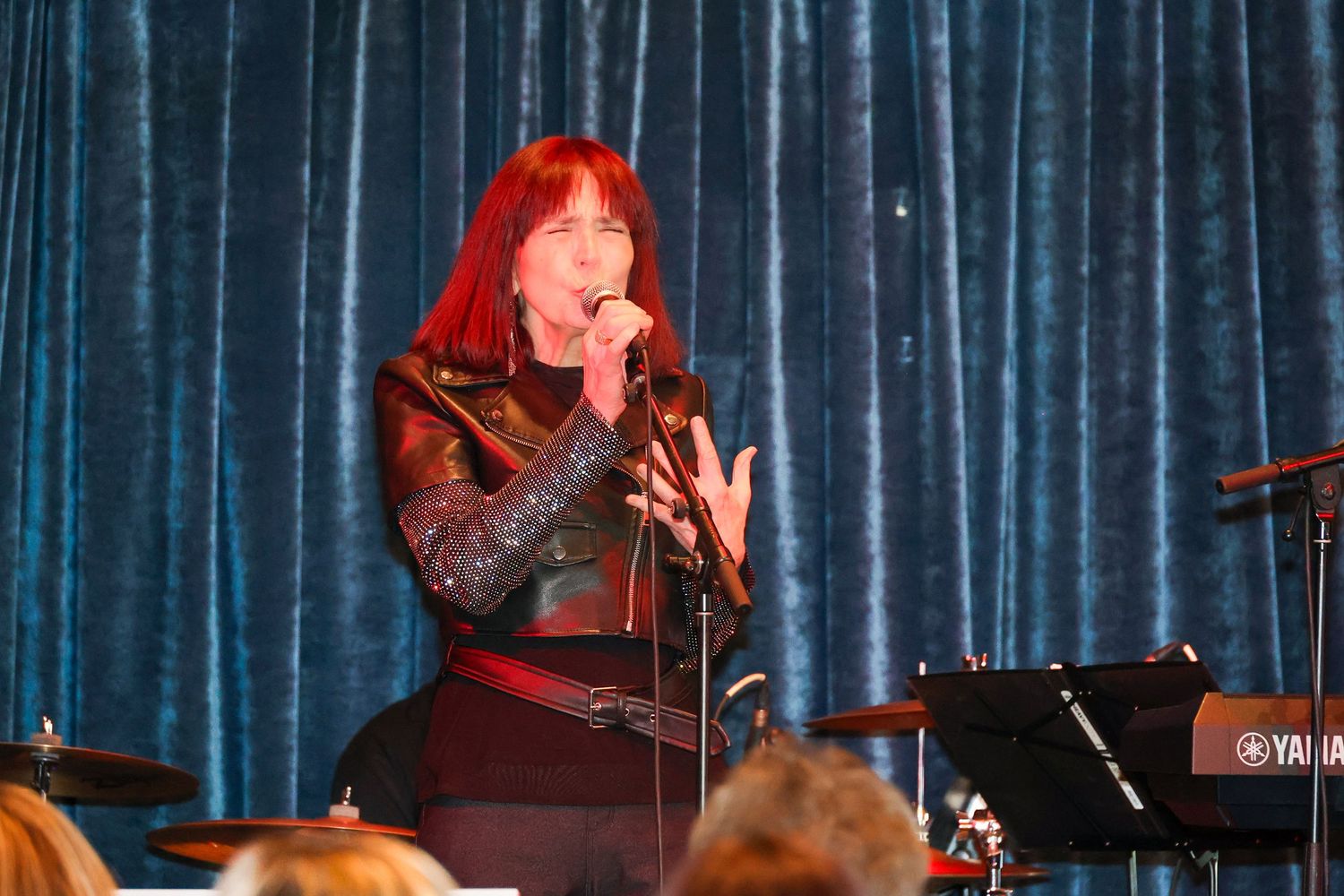 Musicians performing under stage lighting with blue curtain backdrop.