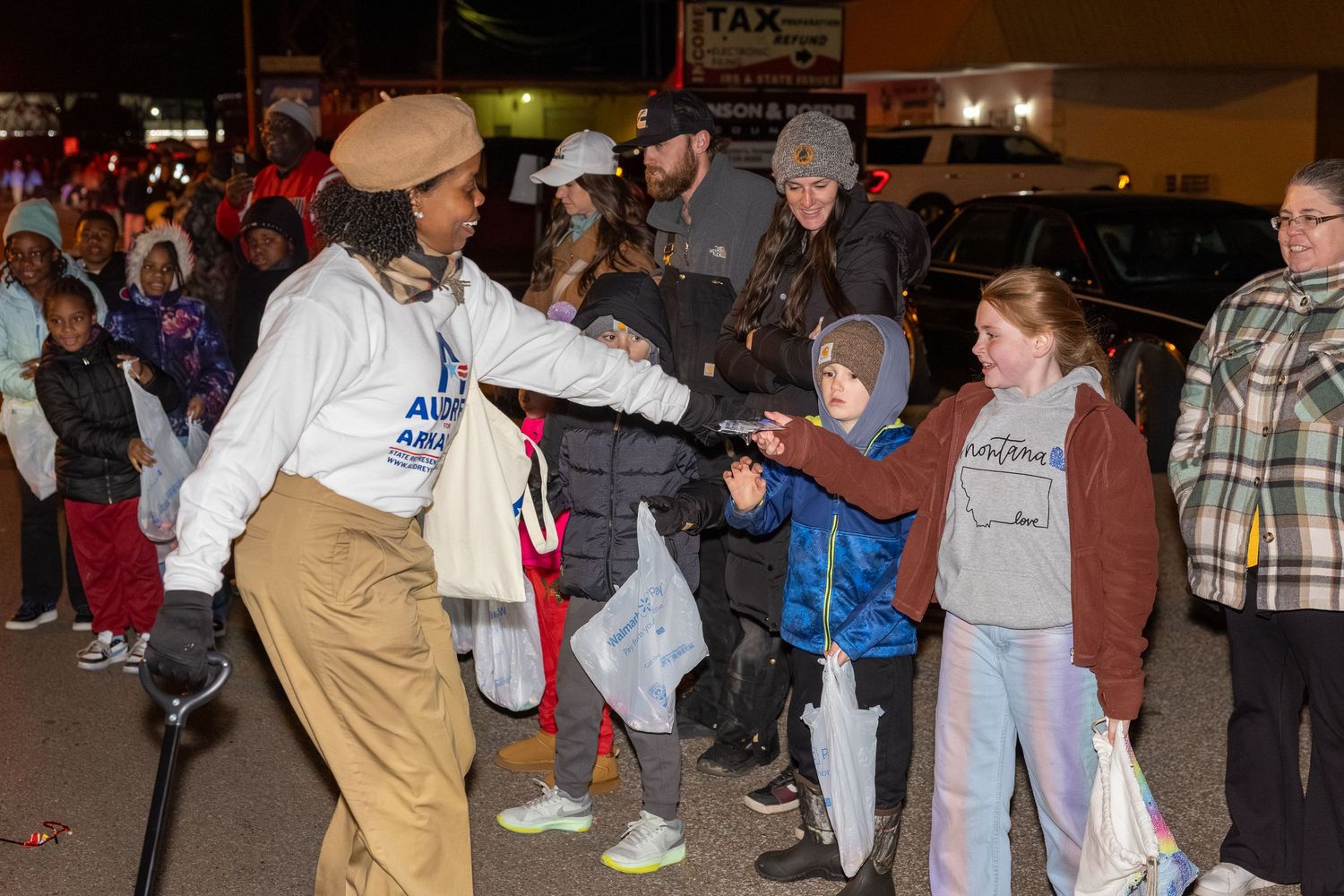 People gathered at a nighttime community event interacting with a costumed performer.