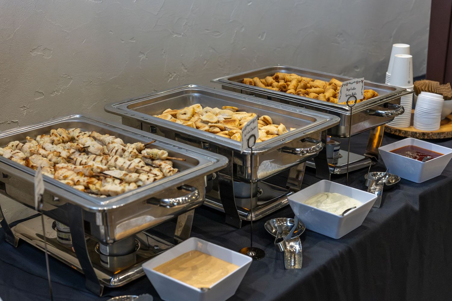 Buffet setup with multiple chafing dishes containing catered food items.
