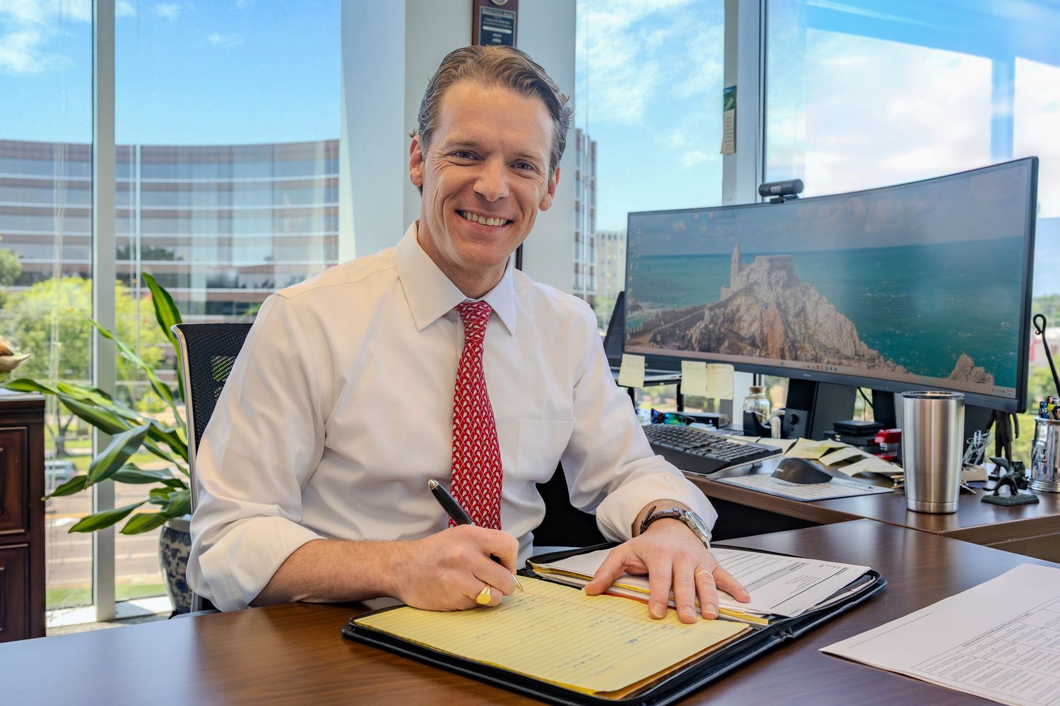 Professional reviewing yellow folders and documents at an office desk.