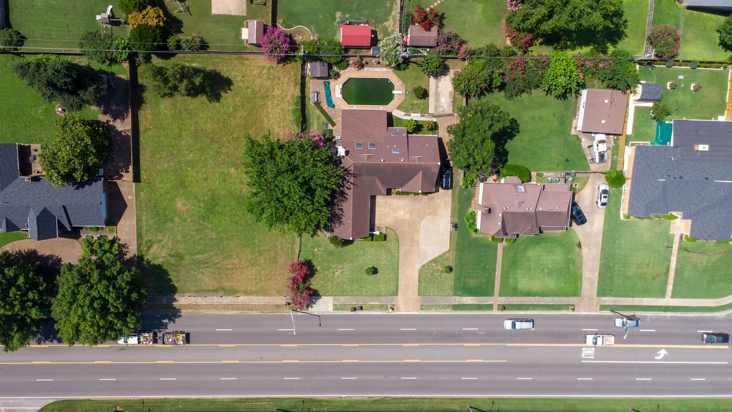 A scenic aerial view of a residential neighborhood with green lawns, houses, and tree-lined streets.
