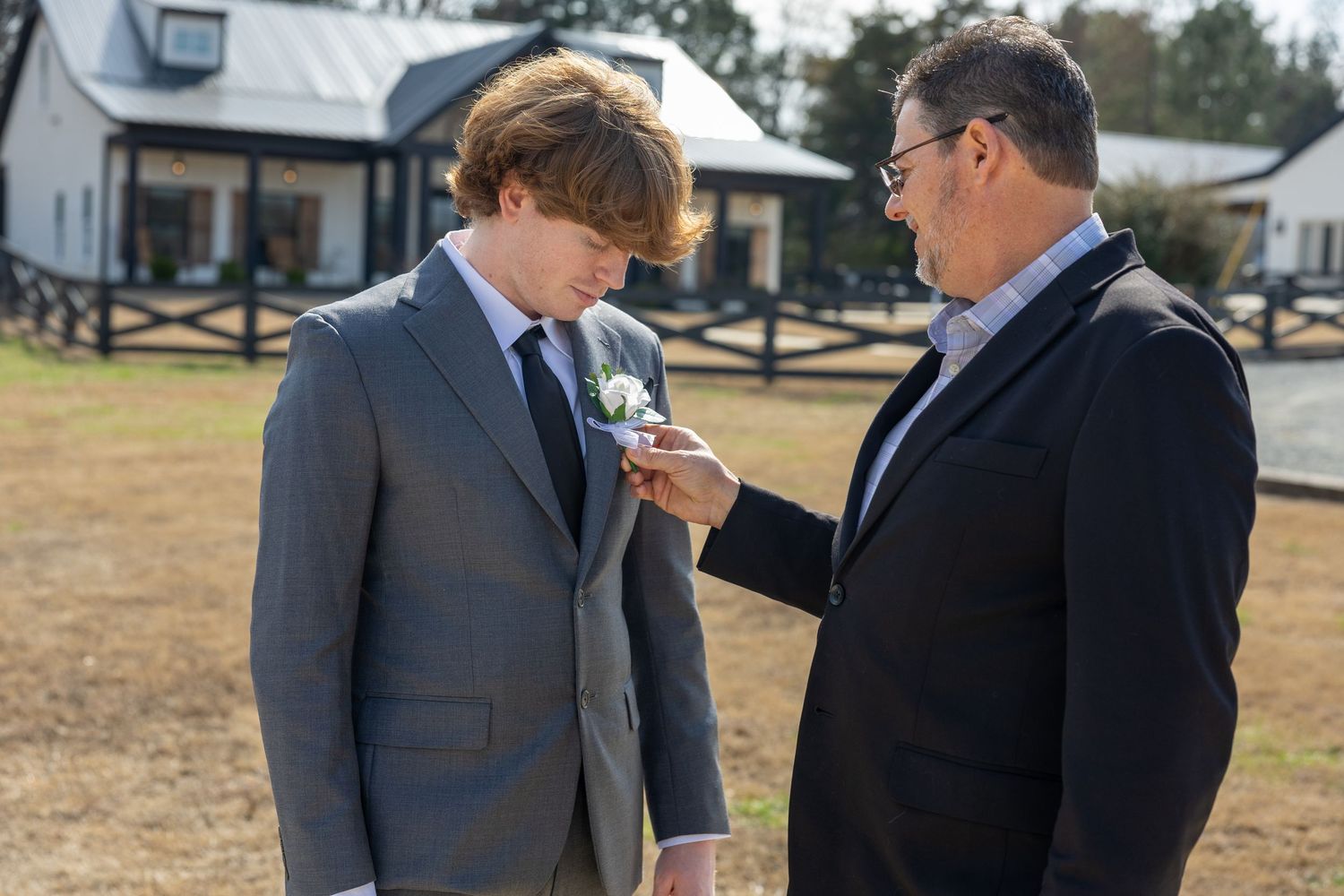 Two people in business suits stand in conversation outdoors on a sunny day.