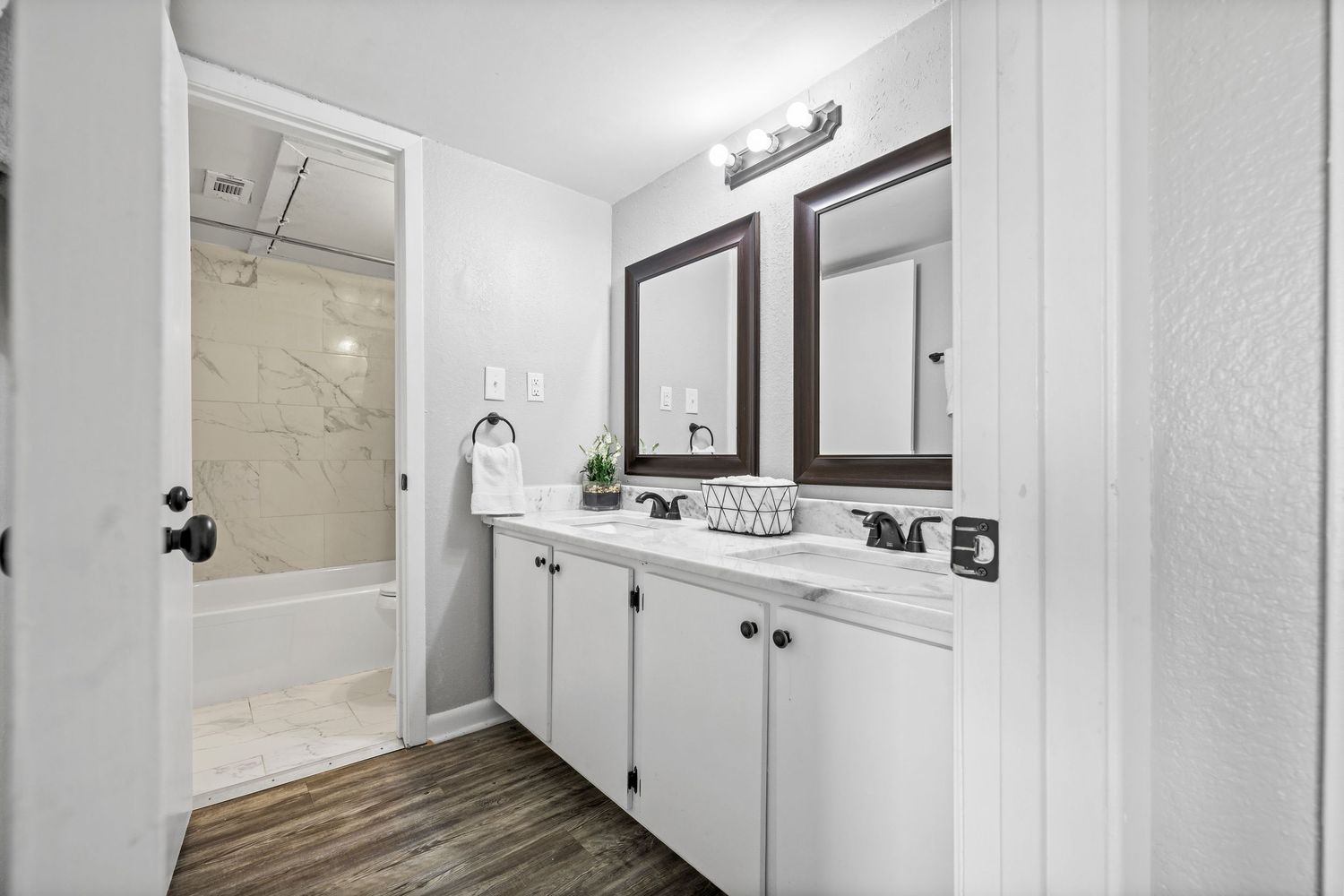 Modern white bathroom interior with vanity cabinet, mirror, and bright lighting fixtures mounted on the wall.