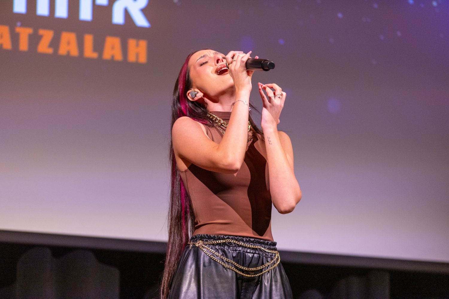 A performer sings passionately into a microphone on stage during a live entertainment event.