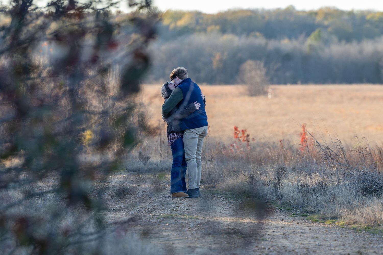 Long-distance view of a proposal taking place in a golden autumn field.