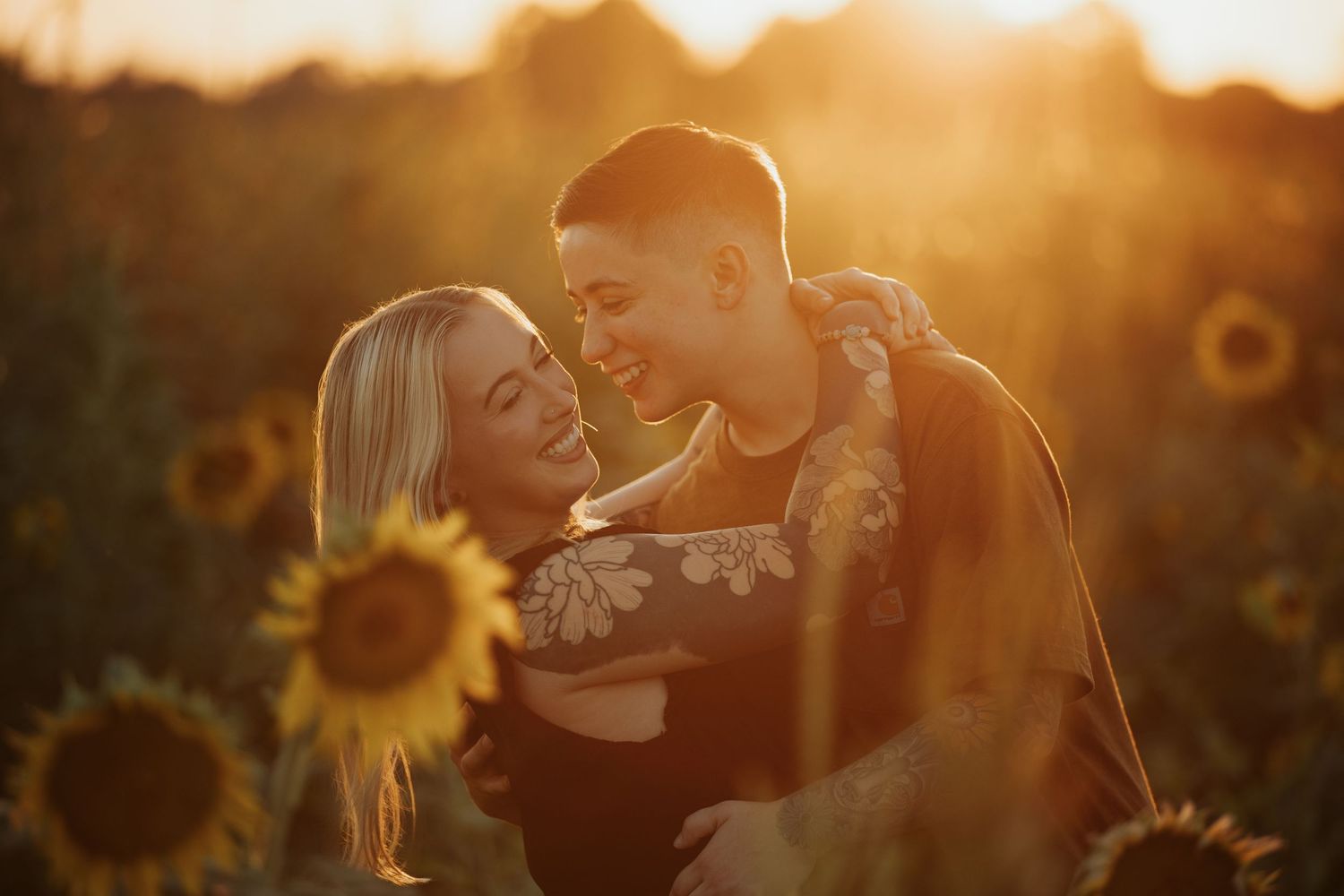 Close-up of couple's tender interaction amid sunflowers during sunset.