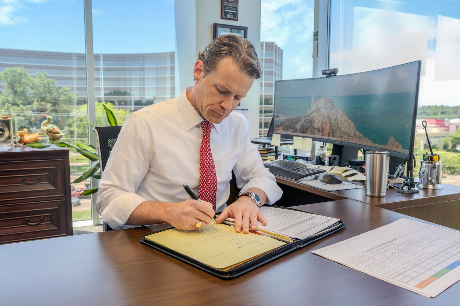 Business professionals reviewing documents at a modern office conference table with natural lighting.