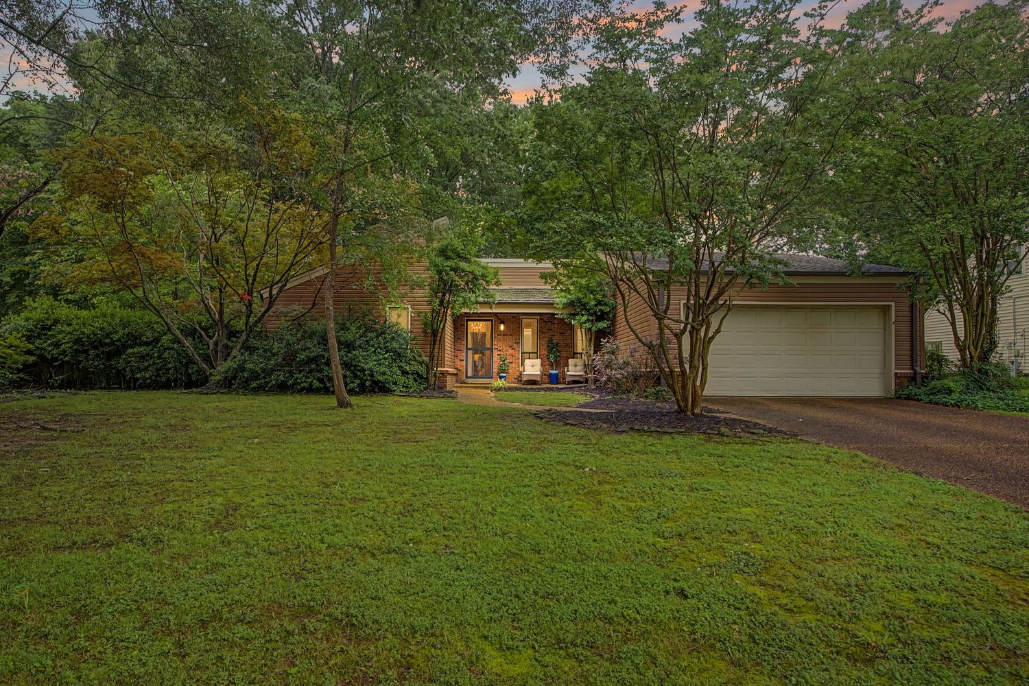 A scenic panoramic view of a residential property with lush green landscaping and a winding driveway.