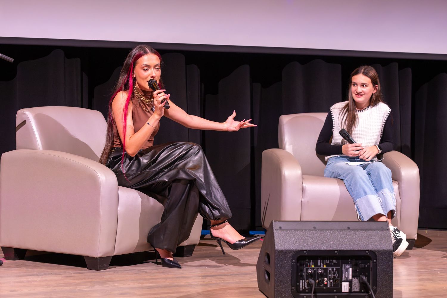 Performer sits on white couch during stage presentation.