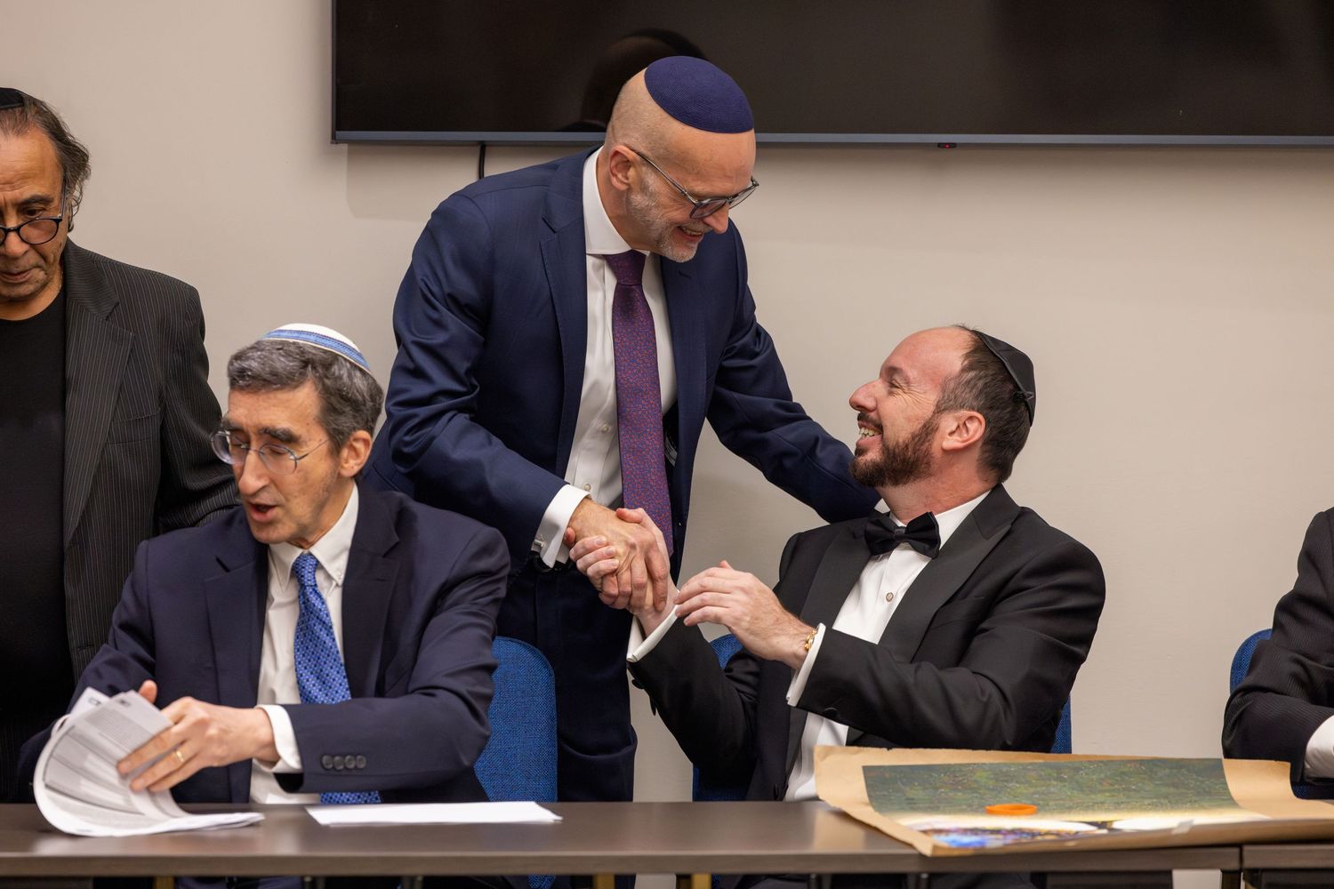Business professionals reviewing documents and signing papers at a conference table.