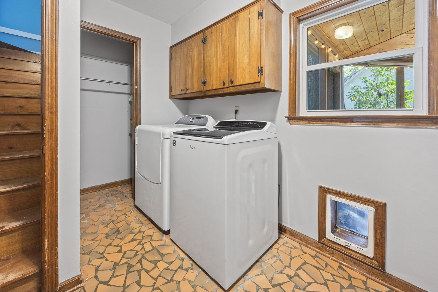 Modern laundry room with white appliances, wood cabinets, and unique patterned flooring.