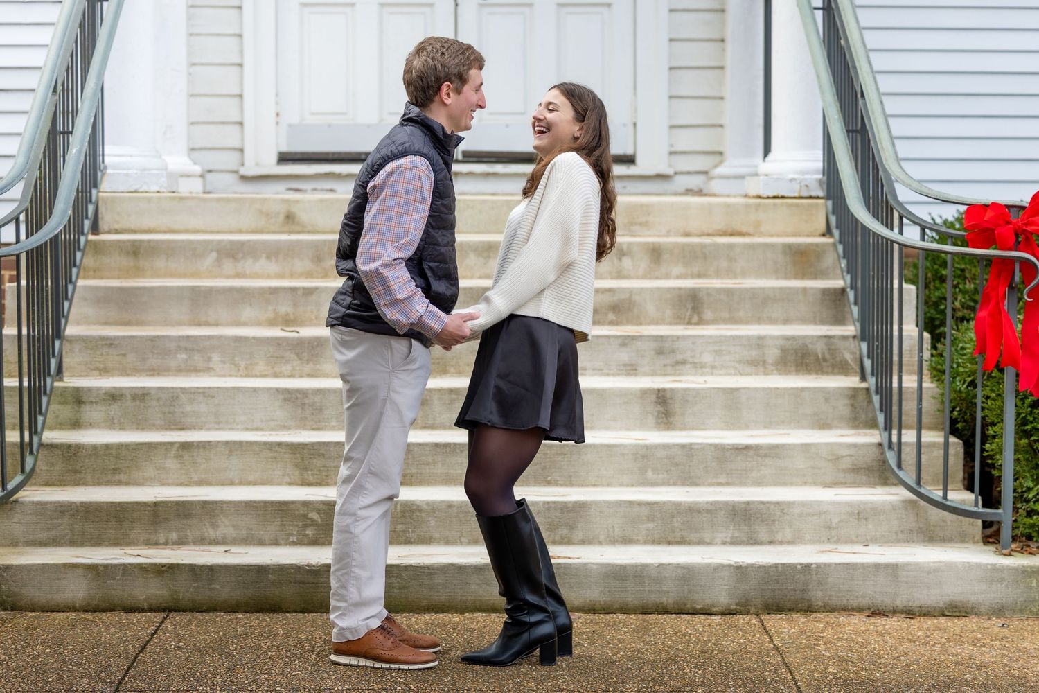A sweet embrace captured on concrete steps leading to a white door with festive red bows.