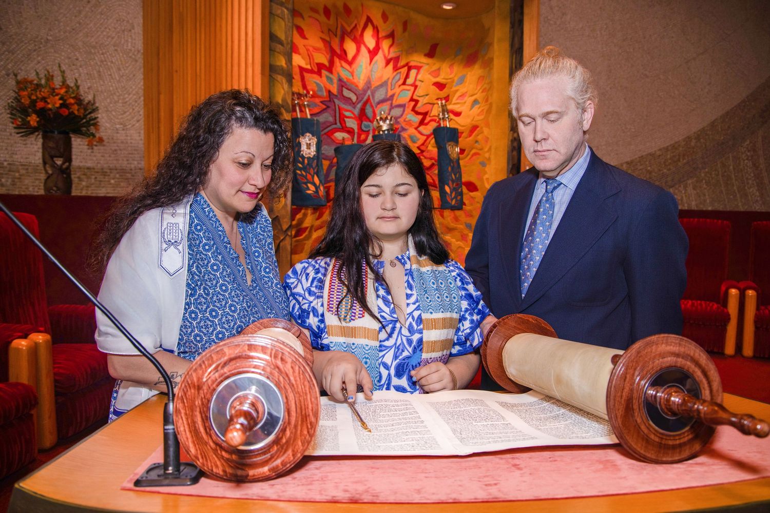 People gathered around a table signing documents in a warm-lit room with orange ambient lighting.