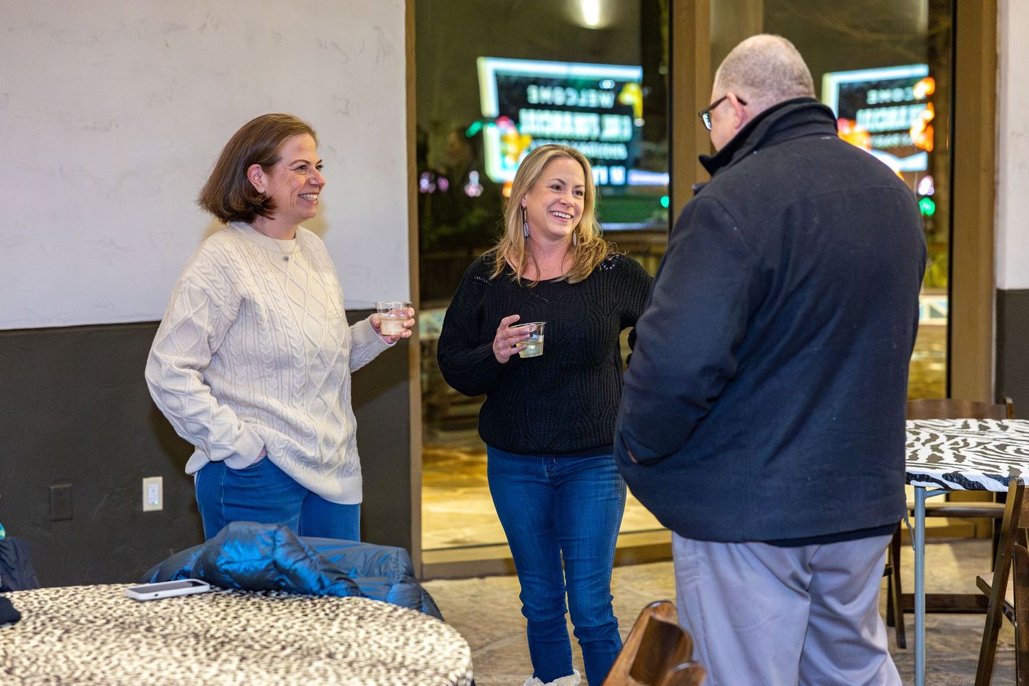 People mingling at an indoor corporate holiday gathering.