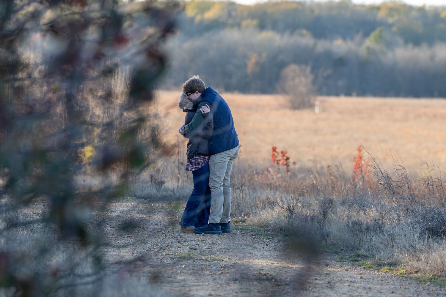 A romantic couple stands together on a trail during golden hour.