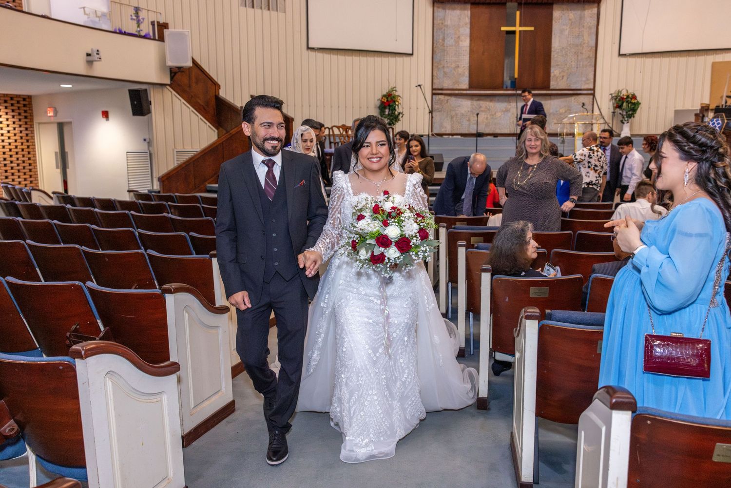 Wedding ceremony in progress inside traditional church sanctuary with wooden pews.