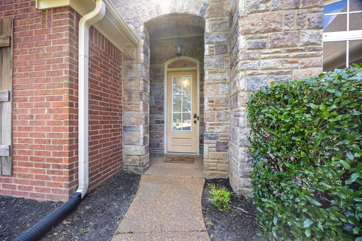 Stone and brick facade entrance with covered walkway and architectural details.