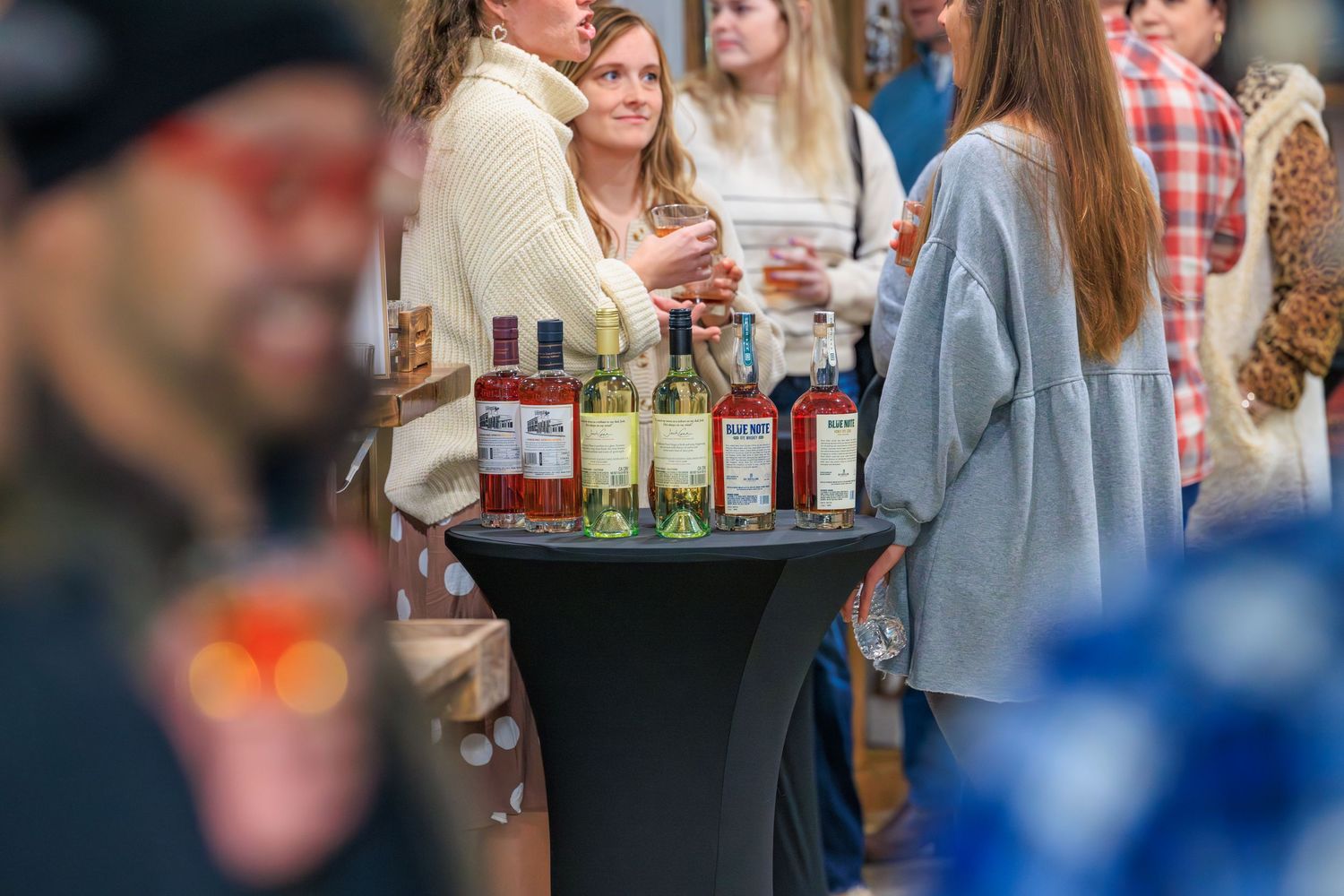 A group of people enjoying drinks and appetizers at a social gathering with a server carrying a tray of beverages.