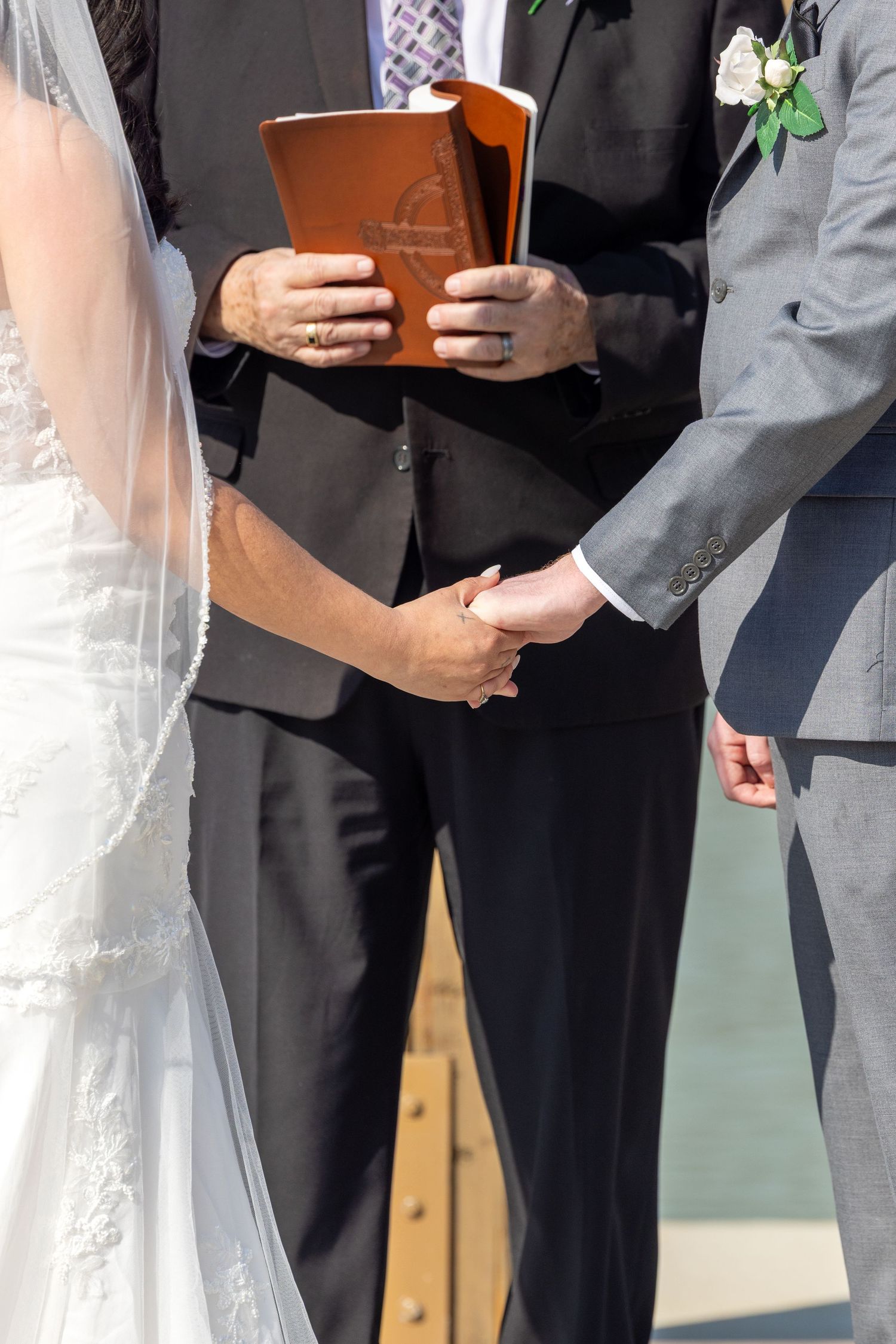 Wedding ceremony participants stand together holding books during an outdoor service.