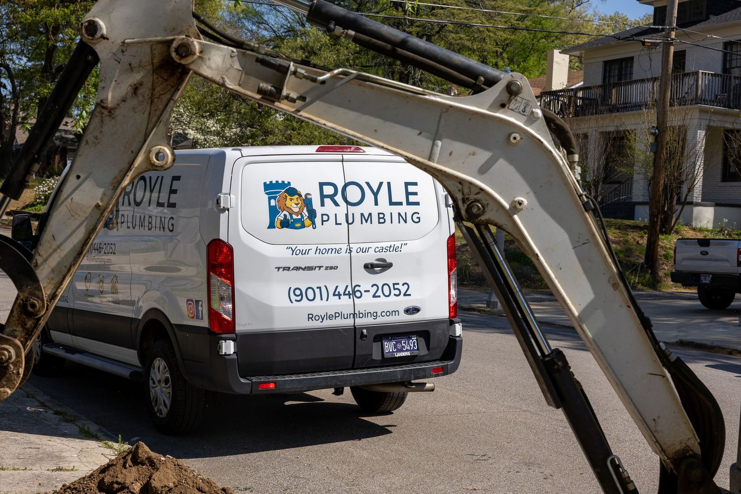 Royle Plumbing branded white service van parked near excavator at outdoor plumbing job site in Memphis.