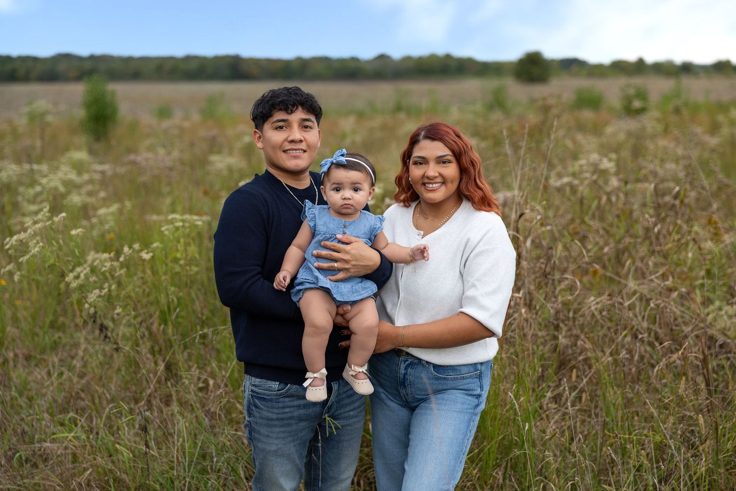 Casual outdoor family portraits captured in a field with golden sunlight and natural scenery.