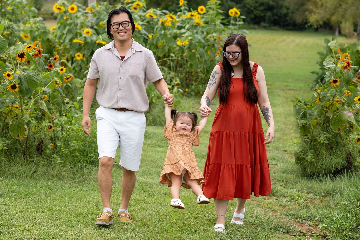 Family walking through a scenic sunflower garden path on a sunny day.