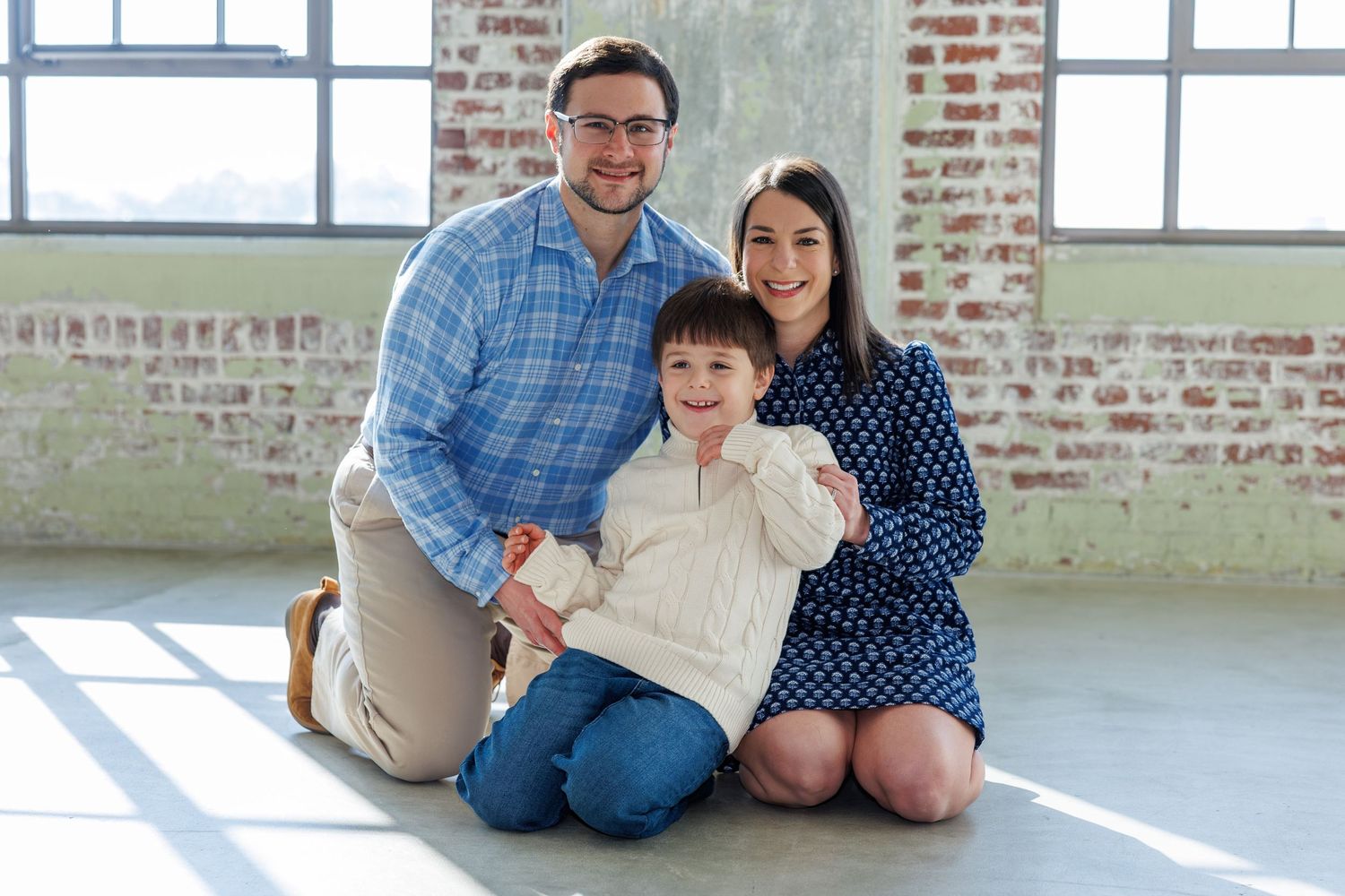 Indoor family portrait session in industrial loft space with brick walls and natural light.