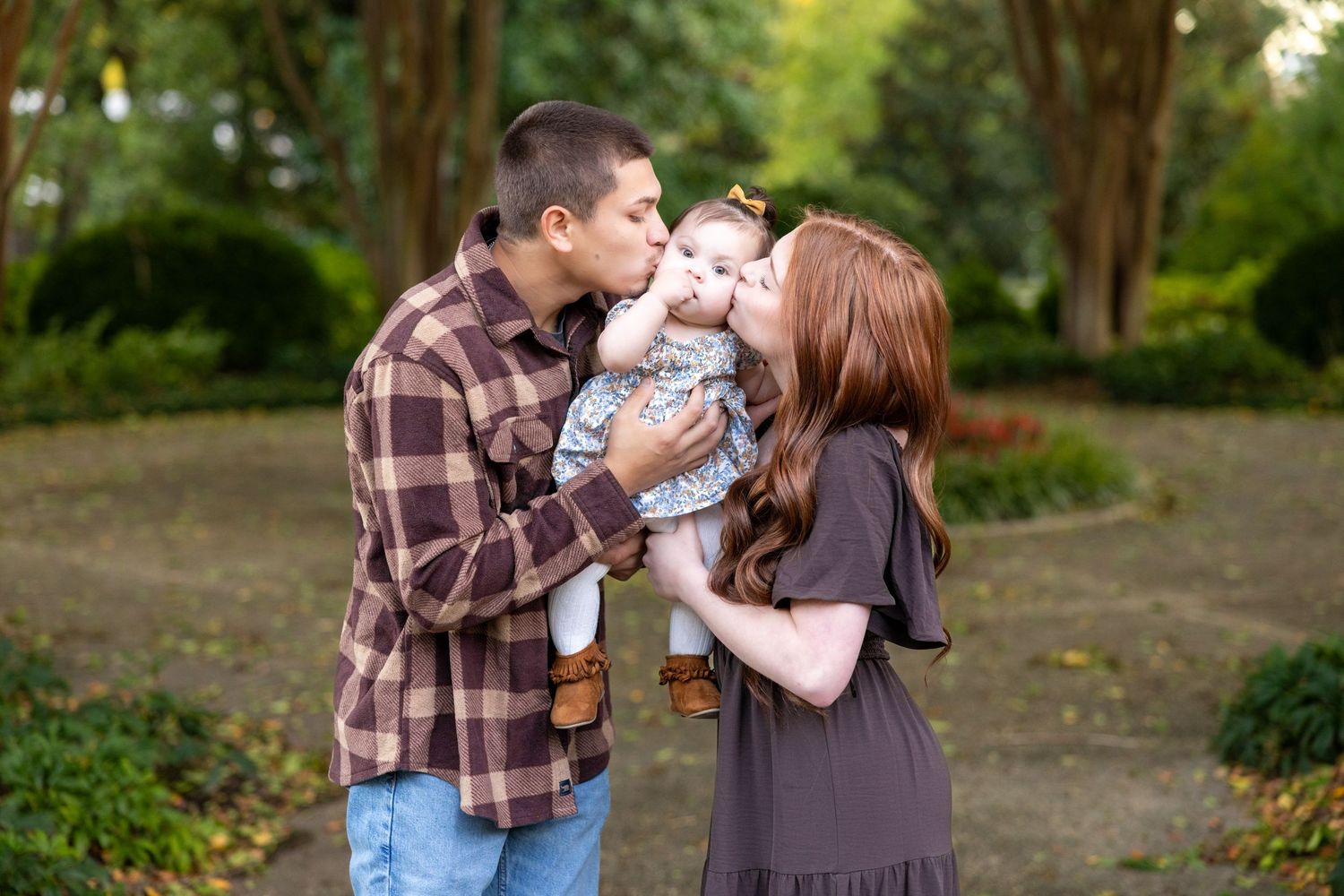 A family sharing a tender moment together outdoors in a park setting.