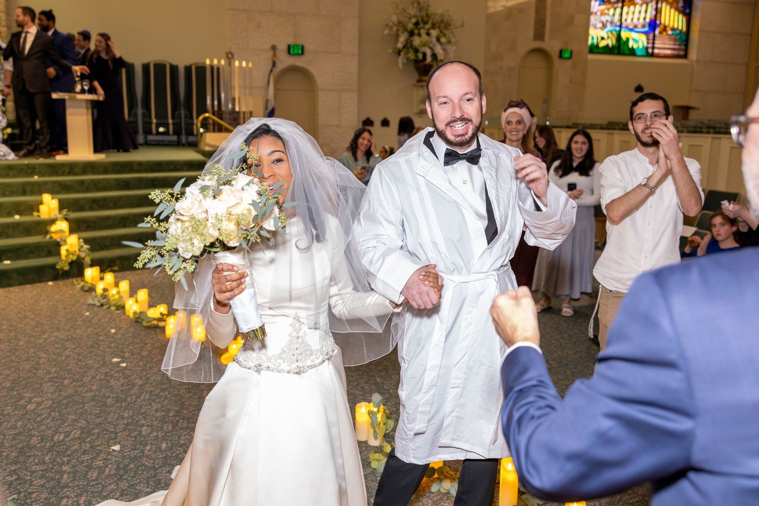 Wedding celebration inside church with decorative lighting and floral arrangements.