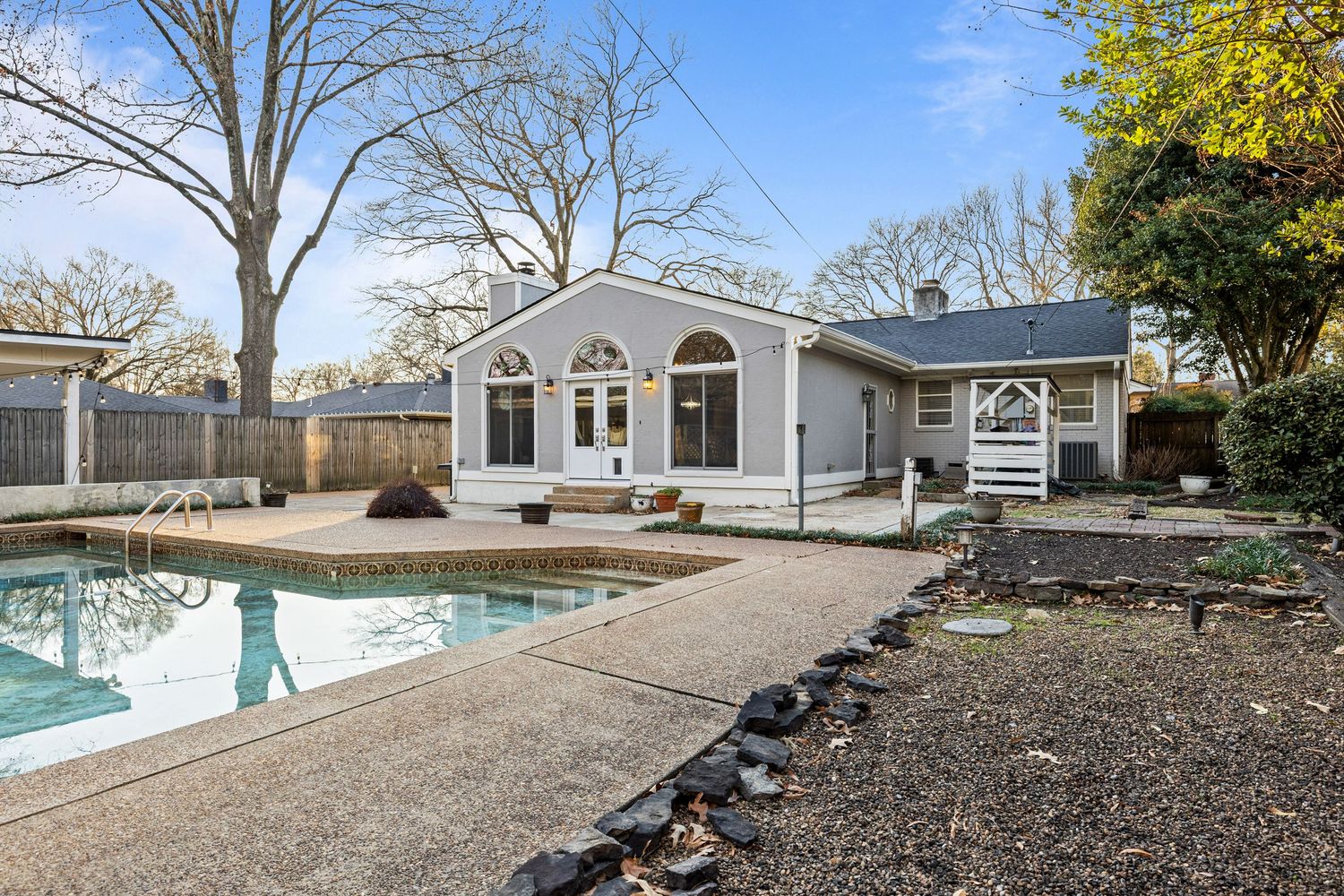 Backyard landscaping project showing mulched garden beds and stone pathway leading to white house in winter setting.