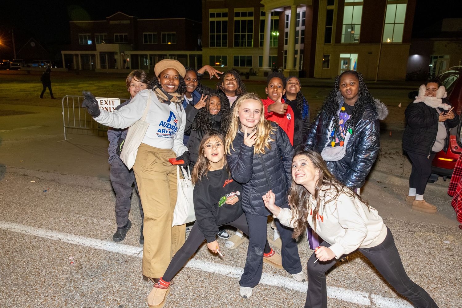Group of people posing energetically at a nighttime outdoor event.