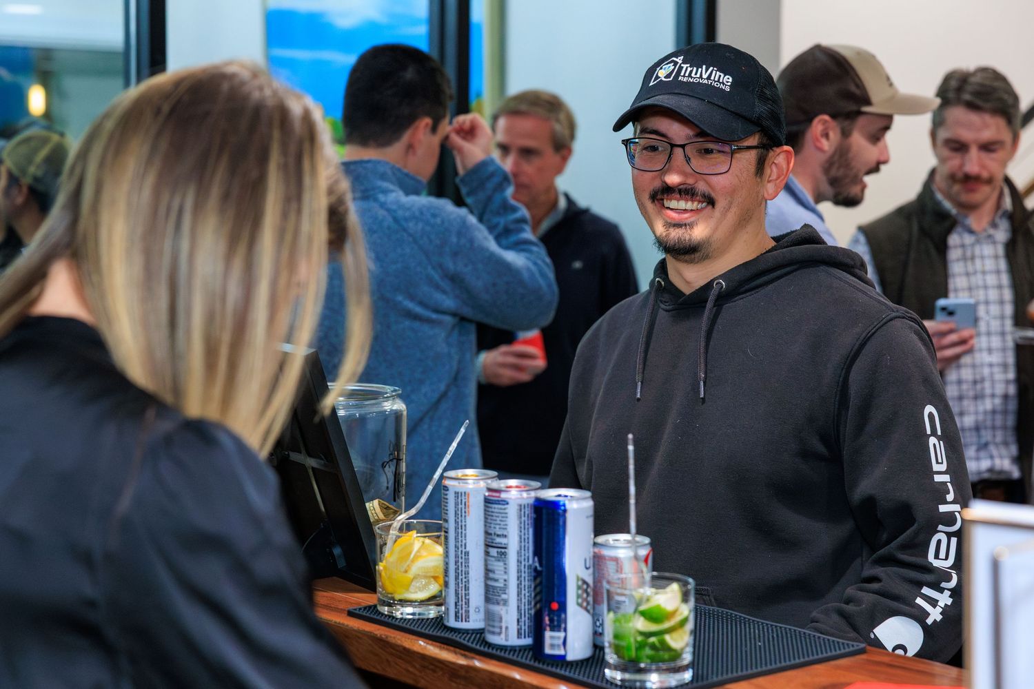 A group of people enjoying drinks and socializing at an outdoor patio bar area.