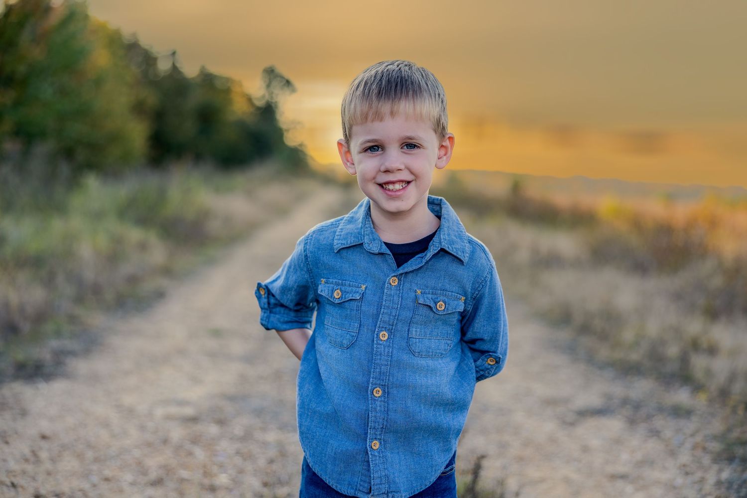 Children in denim outfits smiling during outdoor golden hour photo session.