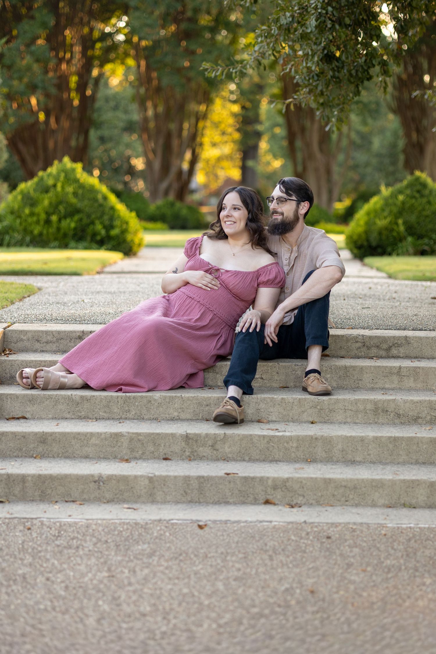 Couple relaxes together on concrete steps in a park during sunset.
