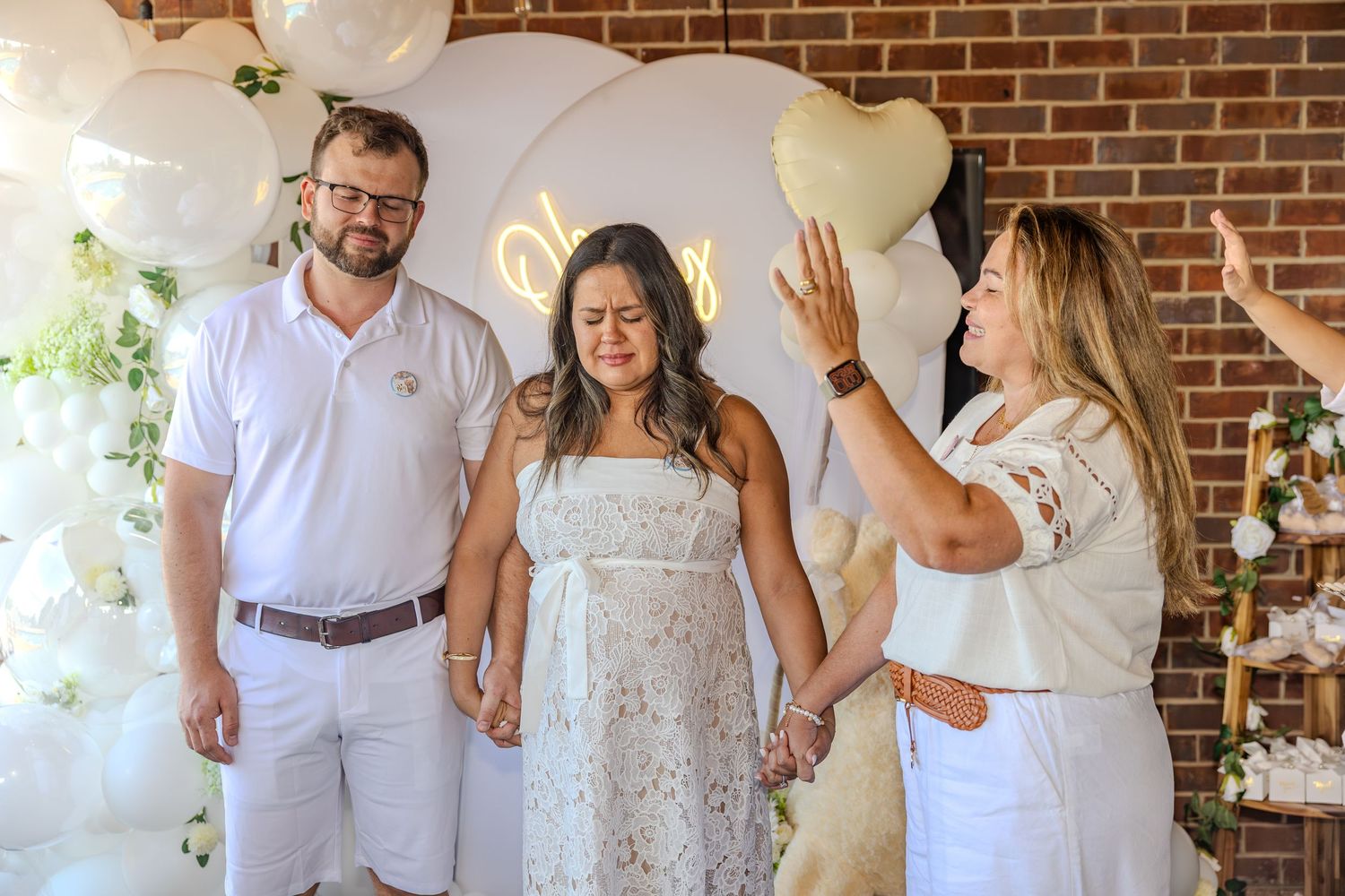 Wedding celebration in a rustic brick-walled venue with white decor and floral arrangements.