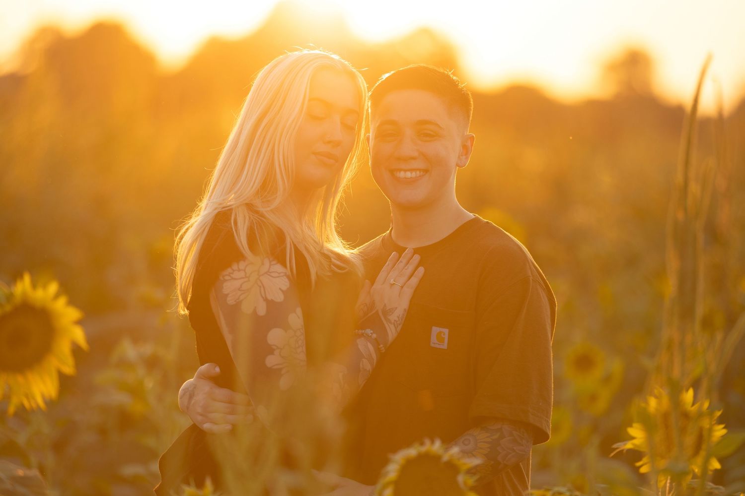 Couple sharing intimate moment among blooming sunflowers at sunset.