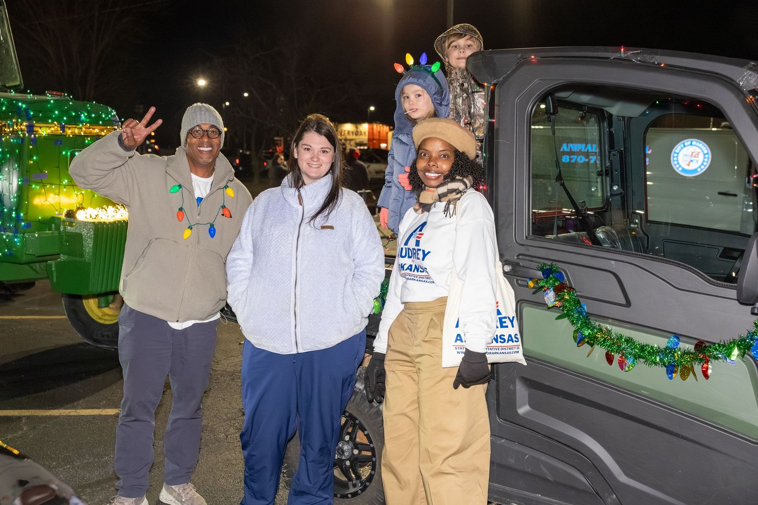 People gather around vehicles at night during outdoor community gathering.