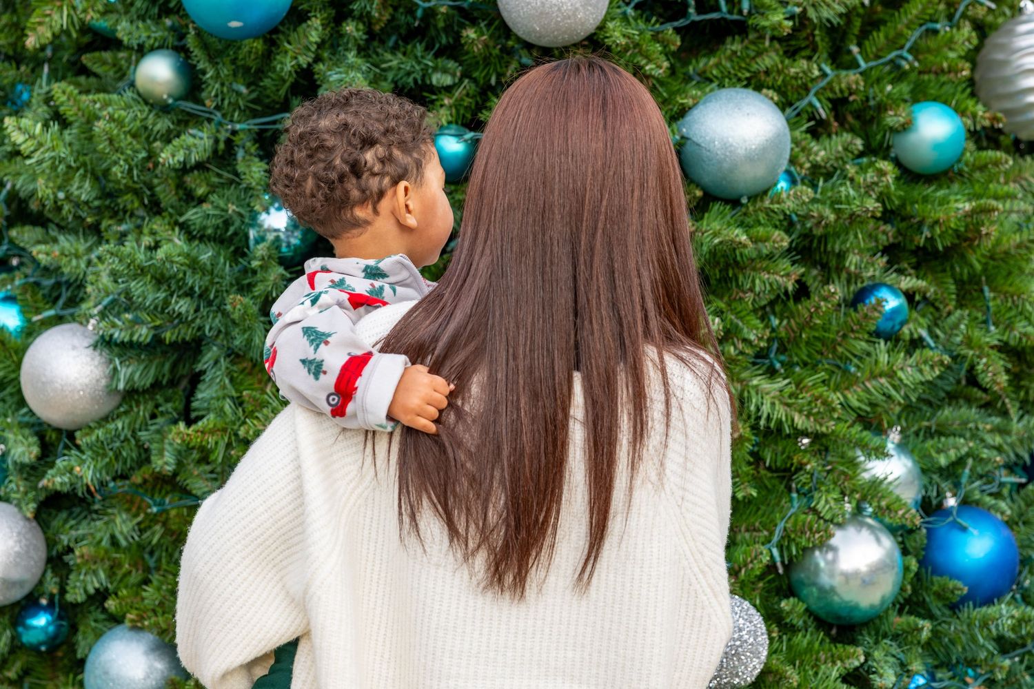 Evergreen Christmas tree decorated with blue and white ornaments in an outdoor setting.