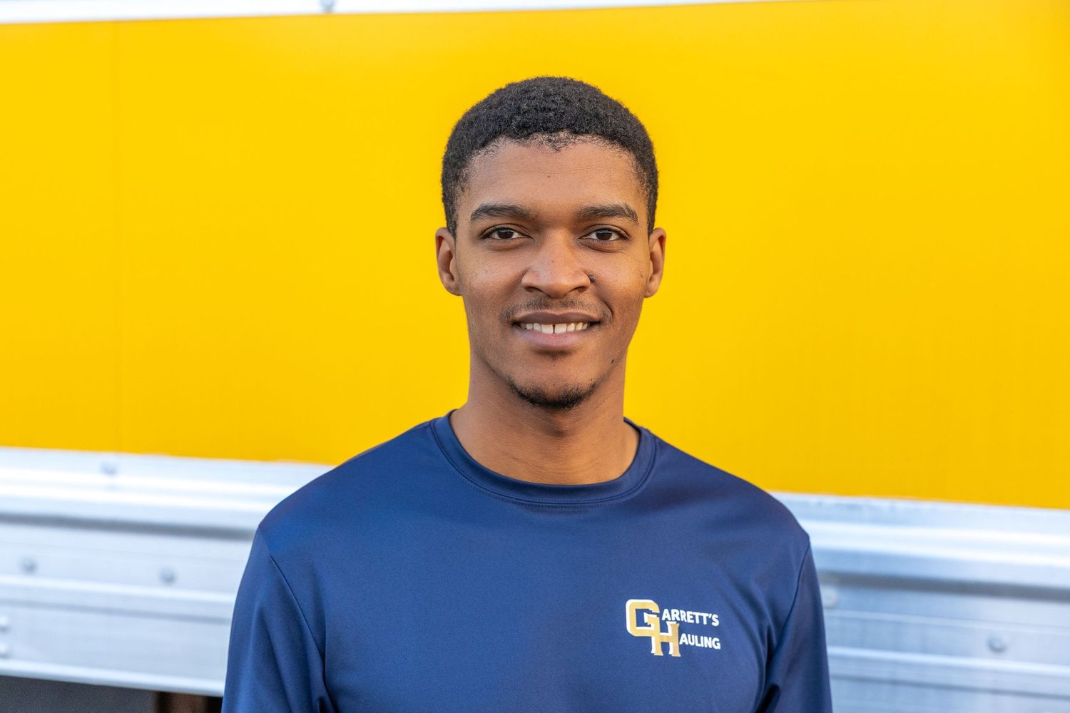 Staff members in matching navy blue uniforms posed against bright yellow background.