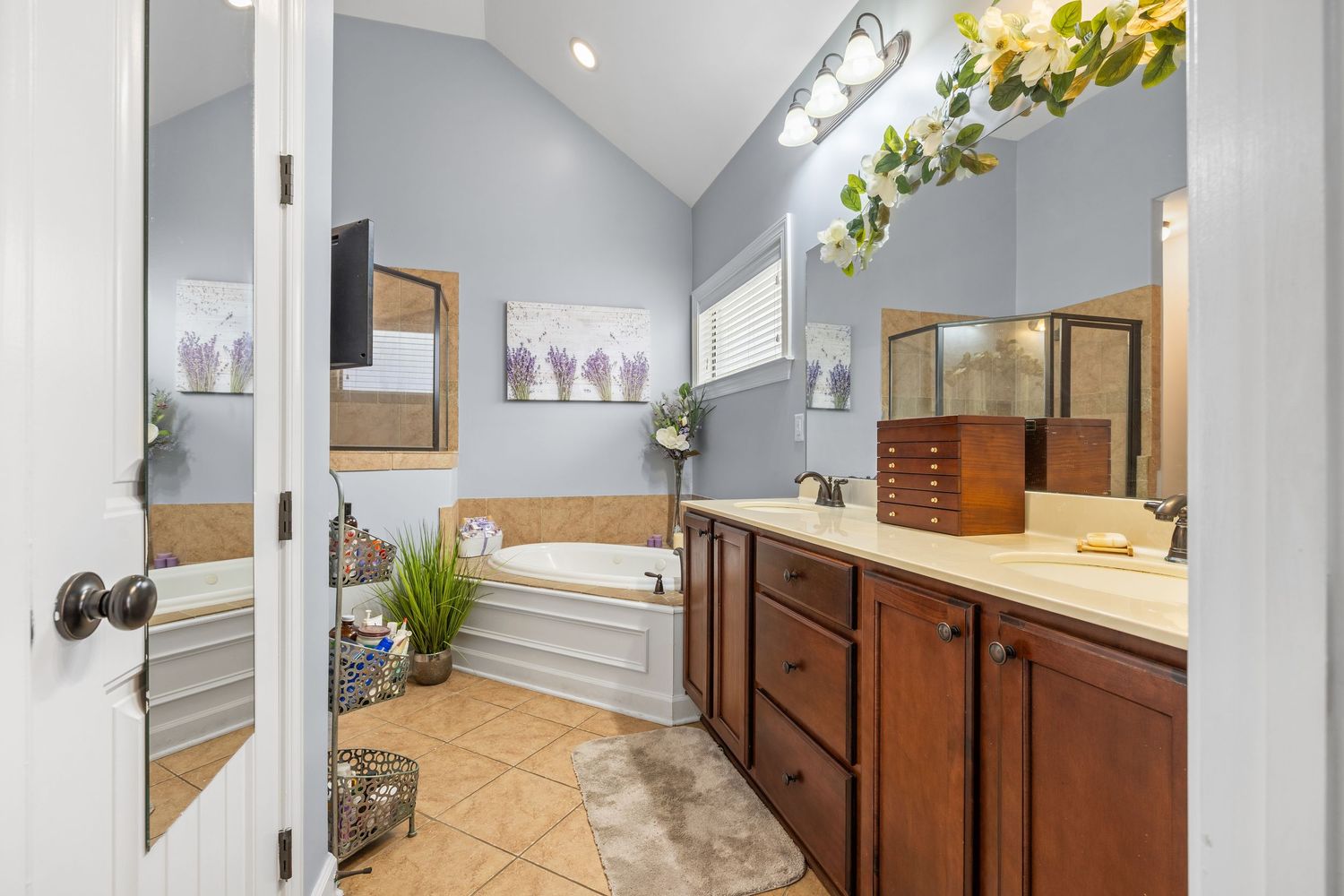 Bright bathroom interior with vaulted ceiling, plants, and wooden cabinetry.