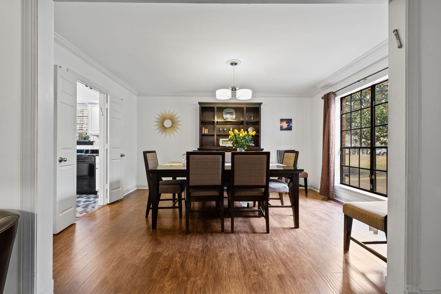 Long view of a modern open floor plan showing dining and living areas with wood flooring.