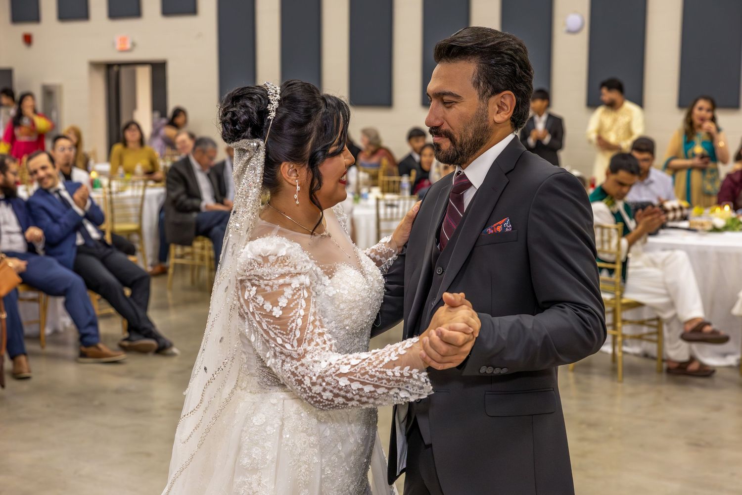 Wedding celebration with traditional Indian attire and dancing in a large reception hall.
