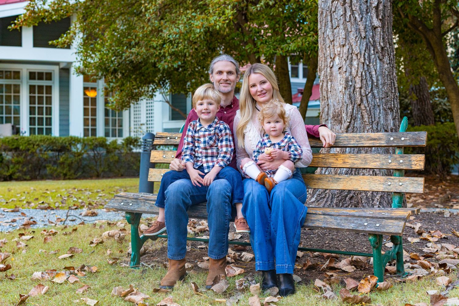Family enjoying a casual outdoor photoshoot together on stone steps surrounded by autumn trees.