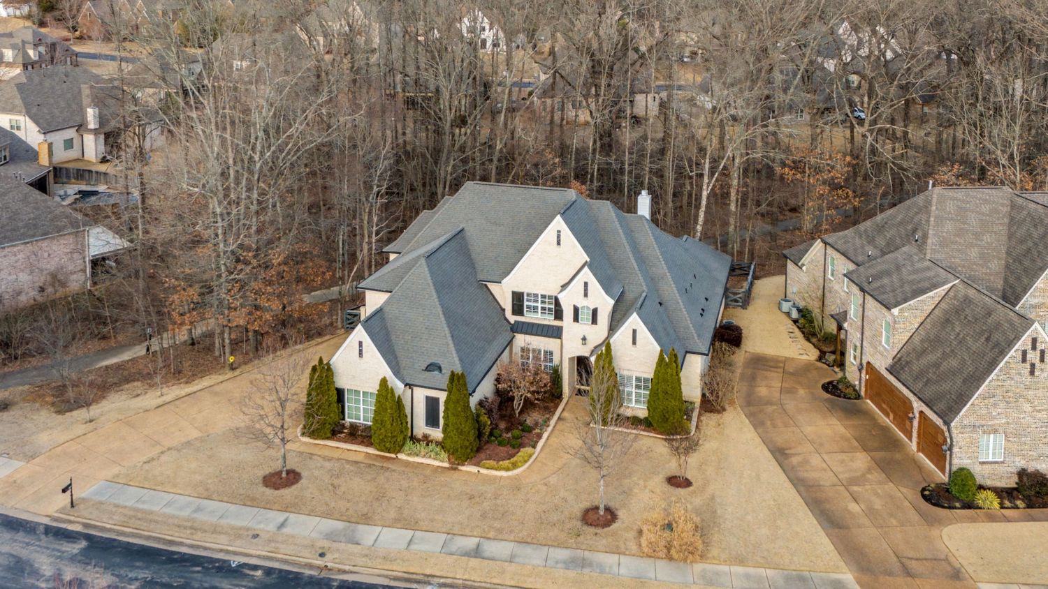 Aerial drone view of a modern two-story home with gray roof and white exterior in a suburban neighborhood.