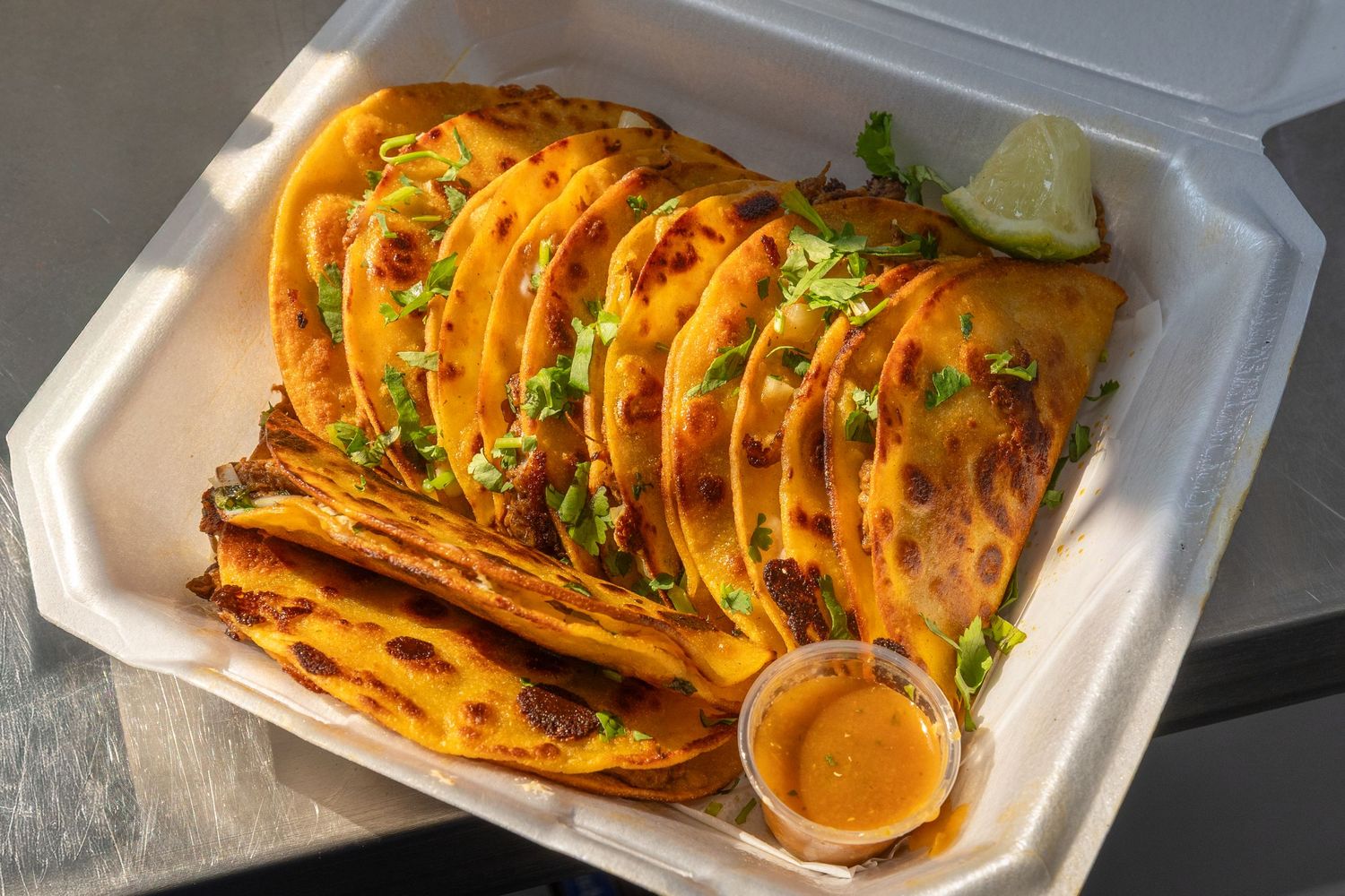 Grilled chicken enchiladas topped with melted cheese and fresh cilantro served in white takeout containers.