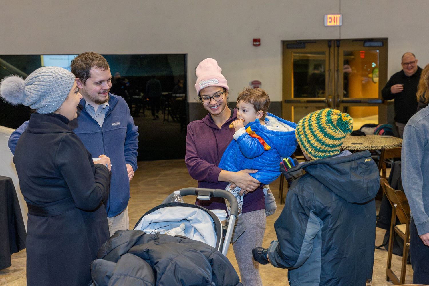Social gathering in community room with casual winter clothing.