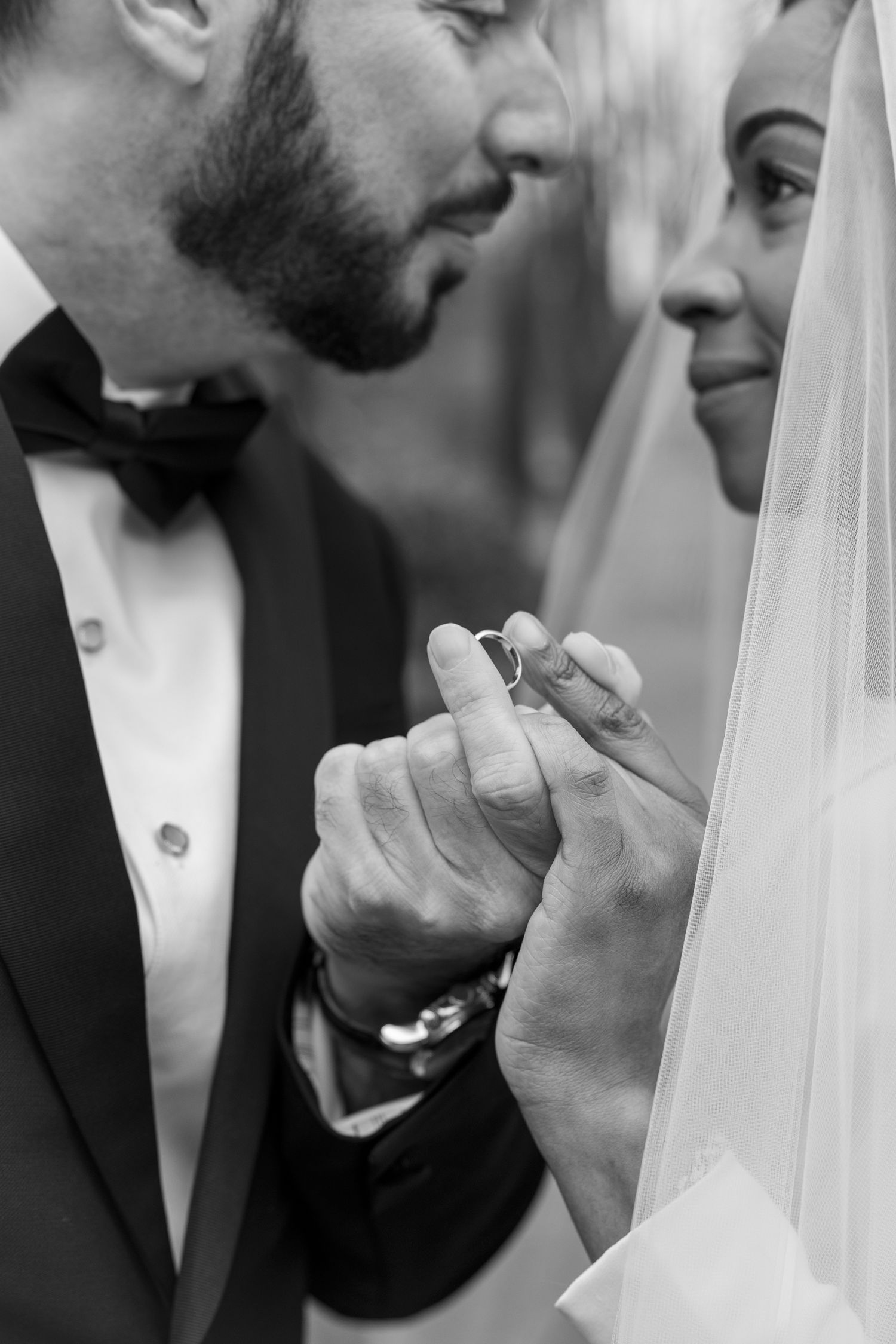 Black and white close-up of tender wedding moment with veil detail.