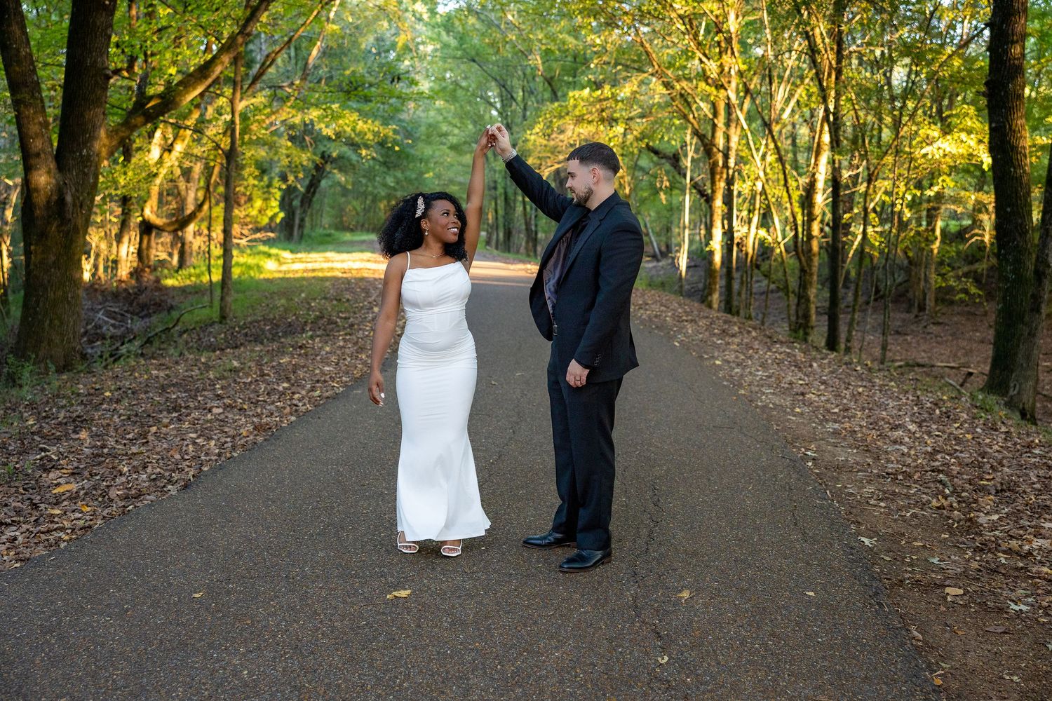 Romantic couple walking together on a gravel path surrounded by autumn trees.